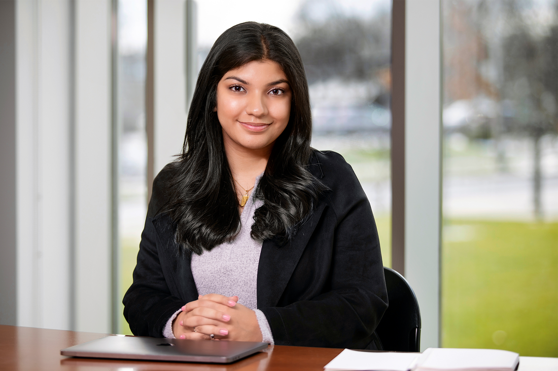 Zainab Kumandan ’22 sitting and smiling.